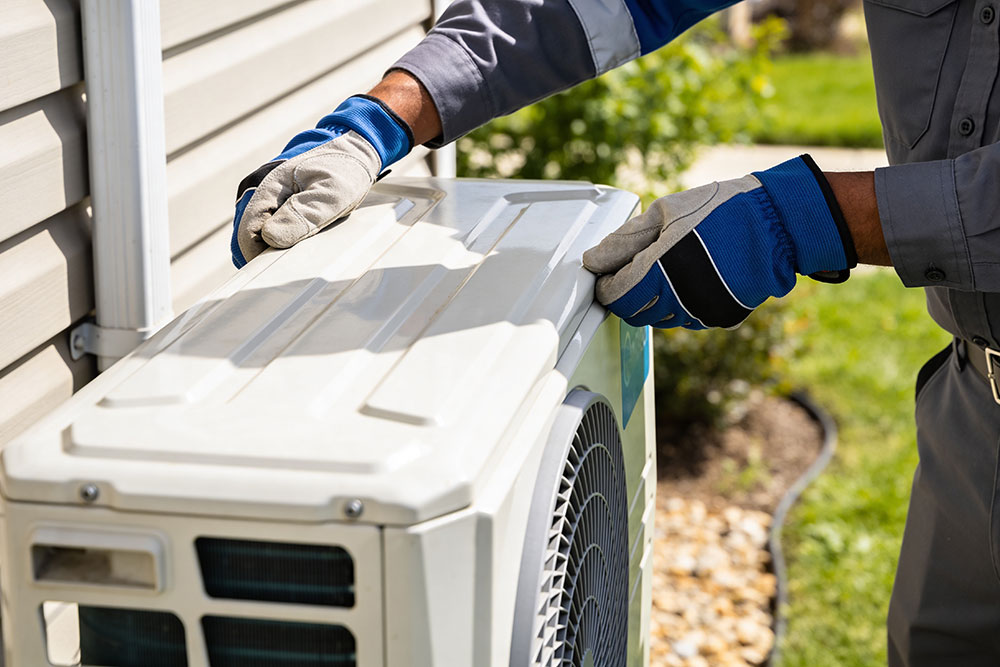 Technician servicing outdoor air conditioning unit in a garden setting.