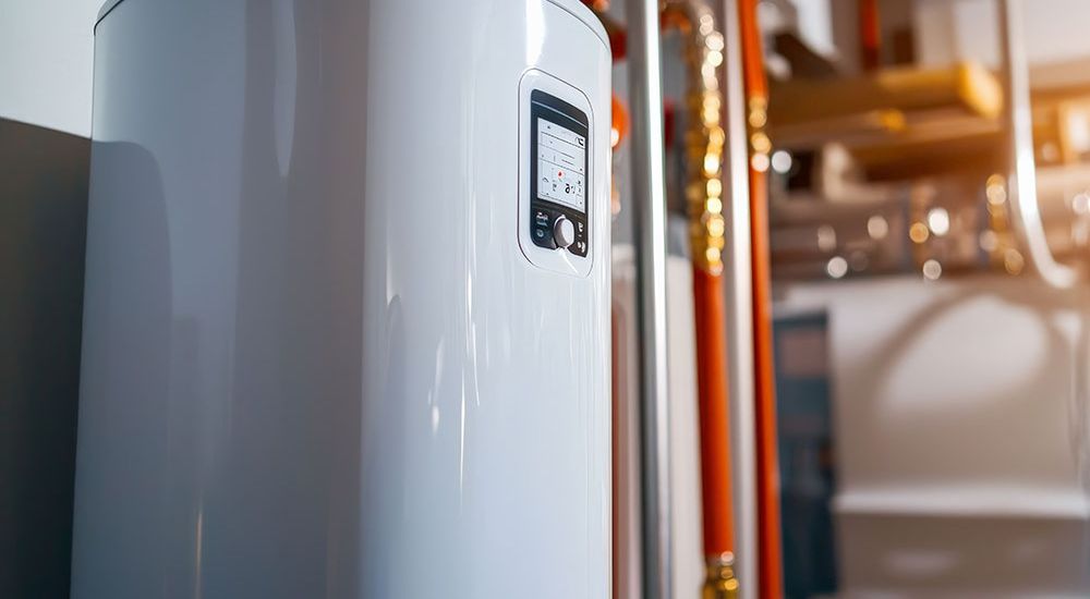 Modern white water heater with digital control panel in a utility room setting.