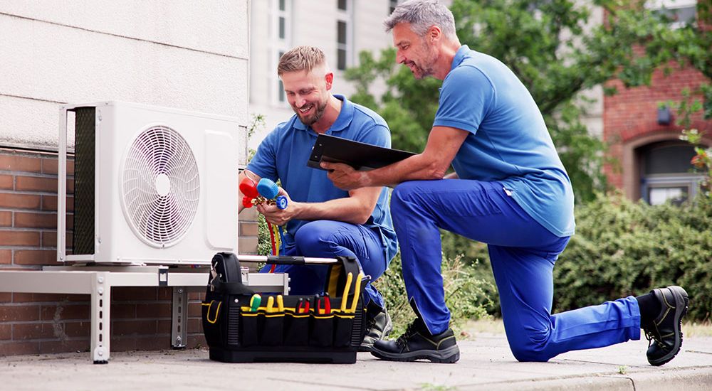 Technicians servicing commercial HVAC unit outdoors with tools and diagnostic equipment.