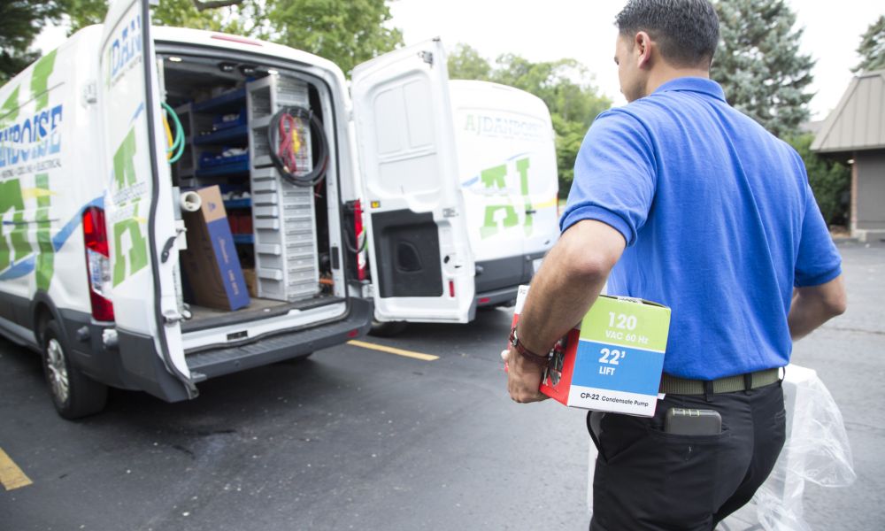 Technician carrying equipment to a service van, ready for electrical or HVAC installation.