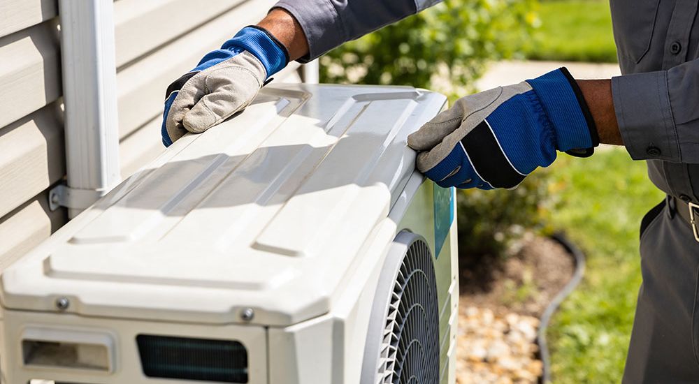 Technician servicing outdoor air conditioning unit in a garden setting.